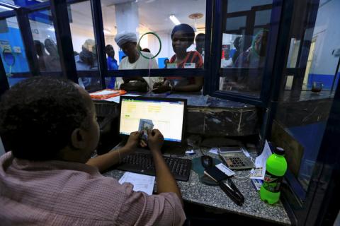 A cashier counts US Dollars as people wait to receive money inside Bab Al-Mandab Exchange transfer money bureau in Khartoum, Sudan, October 7, 2017. PHOTO BY REUTERS/Mohamed Nureldin Abdallah