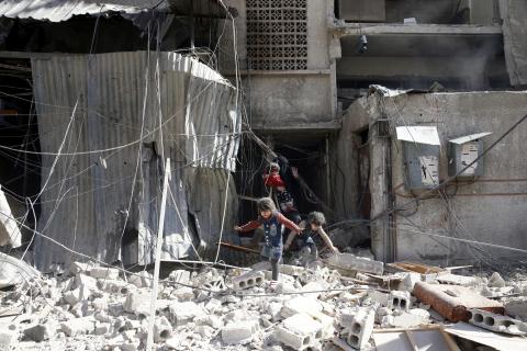 Children walk on rubble of damaged buildings after an airstrike in the besieged town of Douma in eastern Ghouta in Damascus, Syria, February 7, 2018. PHOTO BY REUTERS/ Bassam Khabieh