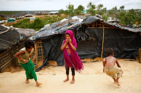 A Rohingya refugee girl reacts to the camera while two other children busy to play marble at the Kutupalang Makeshift Refugee Camp in Cox's Bazar, Bangladesh, July 8, 2017. PHOTO BY REUTERS/Mohammad Ponir Hossain