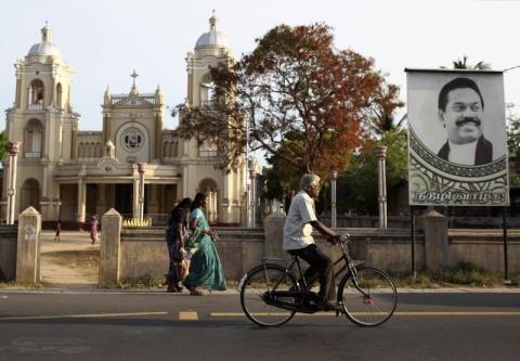 A man cycles past St. James Church and a poster of Sri Lankan President Mahinda Rajapaksa which reads "May you live a long life" in Jaffna, June 6, 2014. PHOTO BY REUTERS/Nita Bhalla