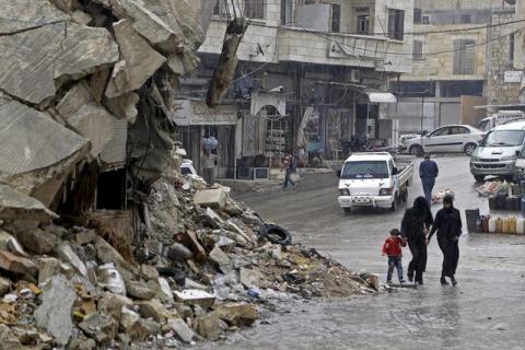 Civilians walk in the rain past a damaged building in the rebel-controlled area of Maaret al-Numan town in Idlib province, Syria, October 28, 2015. PHOTO BY REUTERS/Khalil Ashawi