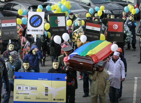 People dressed in outfits of various popular professions in Ukraine carry a coffin symbolising Ukraine's Euro-association and an airplane ticket back to Brussels to the EU Delegation building in Ukraine during a symbolic funeral procession