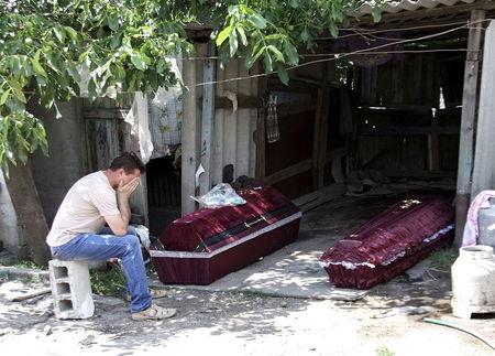 A man, whose mother according to locals was killed by an early morning shelling, reacts while sitting near her coffin, outside the damaged house before her funeral in Donetsk, Ukraine, in this July 7, 2015 file photo. PHOTO BY REUTERS/Igor Tkachenko