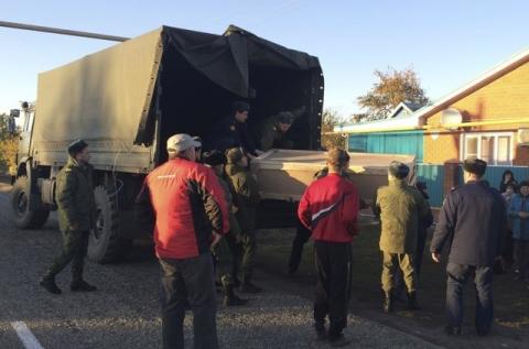 Russian servicemen unload a coffin containing the body of Vadim Kostenko, one of the Russian air force's support staff in Syria, from a truck near his family's house in the village of Grechnaya Balka, north-west of Krasnodar, Russia, October 27, 2015. PHOTO BY REUTERS/Maria Tsvetkova