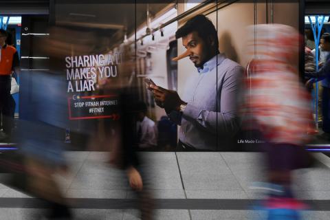 Commuters walk past an advertisement discouraging the dissemination of fake news at a train station in Kuala Lumpur, Malaysia, March 28, 2018. PHOTO BY REUTERS/Stringer