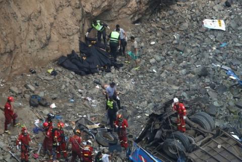 Rescue workers and police work at the scene after a bus crashed with a truck and careened off a cliff along a sharply curving highway north of Lima, Peru, January 2, 2018. PHOTO BY REUTERS/Guadalupe Pardo