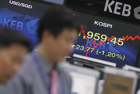 Currency dealers watch a monitor