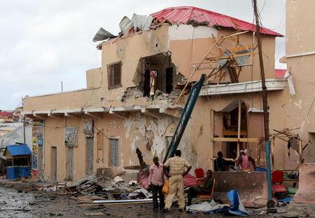 People stand near debris at the scene of an explosion at the gate of Siyad hotel after Friday night's attack in Somalia's capital Mogadishu, July 11, 2015. PHOTO BY REUTERS/Feisal Omar 