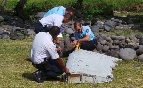 French gendarmes and police inspecting a large piece of plane debris which was found on the beach in Saint-Andre, on the French Indian Ocean island of La Reunion, July 29, 2015. PHOTO BY REUTERS/Prisca Bigot