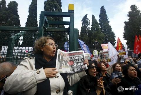 A demonstrator holds a newspaper with the headline "Black day for the press" during a protest outside the Cumhuriyet newspaper headquarters in Istanbul, Turkey, November 27, 2015. PHOTO BY REUTERS/Osman Orsal