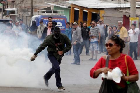 A demonstrator runs to throw a tear gas canister back to the police, during a protest against the re-election of Honduras' President Juan Orlando Hernandez in Tegucigalpa, Honduras January 20, 2018. PHOTO BY REUTERS/Jorge Cabrera