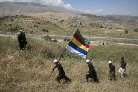 Members of the Druze community walk next to the border fence between Syria and the Israeli-occupied Golan Heights, near the Druze village of Majdal Shams, as others watch the fighting in Syria's ongoing civil war, June 16, 2015. PHOTO BY REUTERS/Baz Ratner
