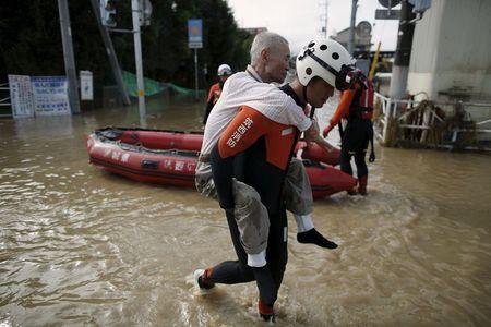 An elderly man is rescued by a firefighter at a residential area flooded by the Kinugawa river, caused by typhoon Etau in Joso, Ibaraki prefecture, Japan, September 11, 2015. PHOTO BY REUTERS/Issei Kato
