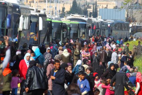 People that were evacuated from the two villages of Kefraya and al-Foua walk near buses, after a stall in an agreement between rebels and Syria's army, at insurgent-held al-Rashideen, Aleppo province, Syria April 15, 2017. PHOTO BY REUTERS/Ammar Abdullah
