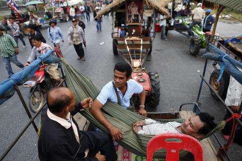 Rice farmers chat among their tractors on a highway where they spent a night in Ayutthaya province