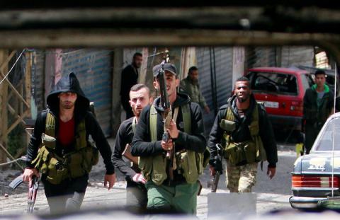 Members of the Palestinian Fatah faction walk with their weapons as seen through a damaged car inside the Ain el-Hilweh refugee camp near Sidon, southern Lebanon, April 11, 2017. PHOTO BY REUTERS/Ali Hashisho