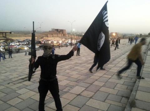 A fighter of the Islamic State of Iraq and the Levant (ISIL) holds an ISIL flag and a weapon on a street in the city of Mosul, in this file photo dated June 23, 2014. PHOTO BY REUTERS/Stringer