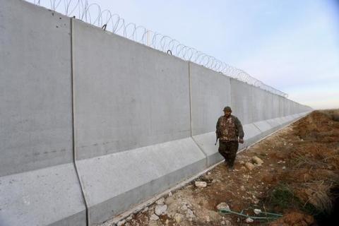 A Kurdish People's Protection Units (YPG) fighter walks near a wall, which activists said was put up by Turkish authorities, on the Syria-Turkish border in the western countryside of Ras al-Ain, Syria, January 29, 2016. PHOTO BY REUTERS/Rodi Said