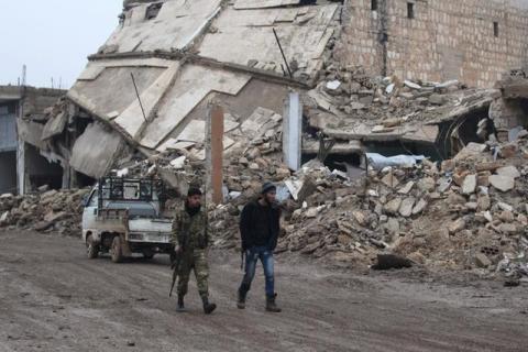 Rebel fighters walk near damaged buildings in al-Rai town, northern Aleppo countryside, Syria, December 30, 2016. PHOTO BY REUTERS/Khalil Ashawi