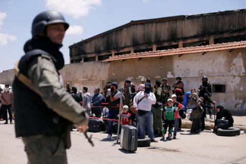 A Syrian security personnel stands guard as rebel fighters and their families evacuate the besieged Waer district in the central Syrian city of Homs, after an agreement reached between rebels and Syria's army, Syria, May 21, 2017. PHOTO BY REUTERS/Omar Sanadiki