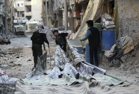 Free Syrian Army fighters pull carpets along a rubble-filled street as they prepare to use them as curtains to provide cover from snipers loyal to Syria's President Bashar al-Assad in Deir al-Zor, eastern Syria