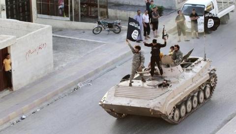Militant Islamist fighters hold the flag of Islamic State (IS) while taking part in a military parade along the streets of northern Raqqa province in this June 30, 2014 file photo. PHOTO BY REUTERS/Stringer