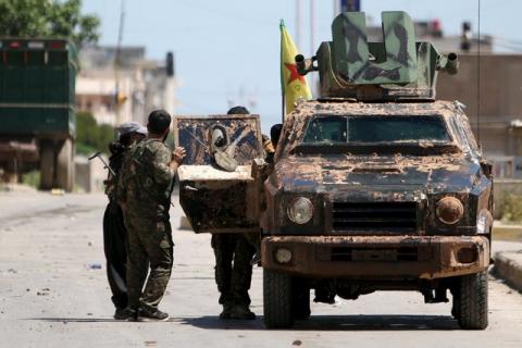 Kurdish fighters from the People's Protection Units (YPG) stand near a military vehilce in the southeast of Qamishli city, Syria, April 22, 2016. PHOTO BY REUTERS/Rodi Said