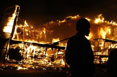 A man watches a burning building after a grand jury returned no indictment in the shooting of Michael Brown in Ferguson, Missouri, November 24, 2014. PHOTO BY REUTERS/Jim Young