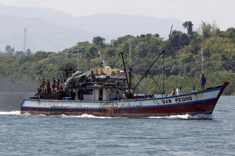 Filipino fishermen wave from a fishing boat bound to fish near Scarborough Shoal in Masinloc, Zambales