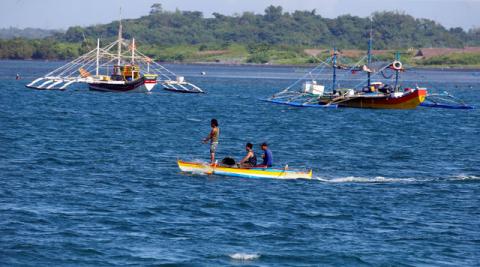 Fishermen ride on a small boat past their big boats as they prepare to fish at disputed Scarborough Shoal, at the coastal village of Cato in Infanta, Pangasinan in the Philippines, November 3, 2016. PHOTO BY REUTERS/Erik De Castro