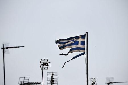 A frayed Greek national flag flutters among antennas atop a building in central Athens, Greece, July 20, 2015. PHOTO BY REUTERS/Alkis Konstantinidis