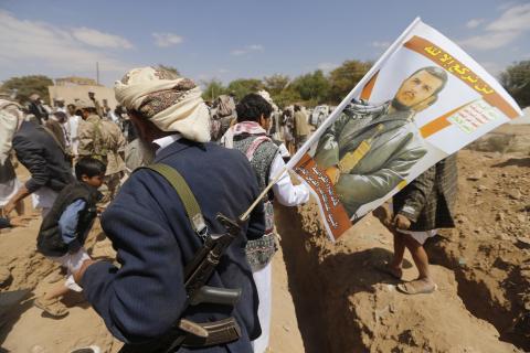 A follower of the Shi'ite Houthi group holds a flag, with the photo of the group's leader Abdul Malik al-Houthi on his rifle, during a mass funeral for victims of a suicide attack on followers of the Shi'ite Houthi group, in Sanaa