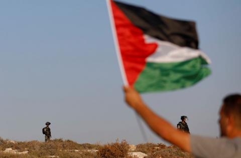 A demonstrator waves a Palestinian flag in front of Israeli border police during a protest against Israeli land seizures for Jewish settlements, in the village of Ras Karkar, near Ramallah in the occupied West Bank, September 4, 2018. PHOTO BY REUTERS/Mohamad Torokman