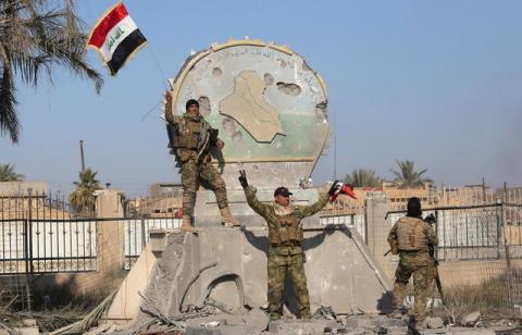 A member of the Iraqi security forces holds an Iraqi flag at a government complex in the city of Ramadi, December 28, 2015. PHOTO BY REUTERS/Stringer