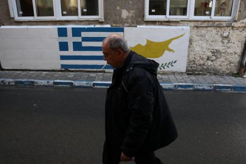 A man walks in front of Greek and Cypriot flags painted on a wall near the UN-controlled buffer zone in Nicosia, Cyprus, January 11, 2017. PHOTO BY REUTERS/Yiannis Kourtoglou
