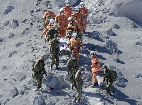 Japan Self-Defense Force (JSDF) soldiers and firefighters carry an injured person near a crater of Mt. Ontake, which straddles Nagano and Gifu prefectures