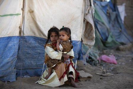 A girl holds her sister outside their tent at a camp for people displaced by recent fighting between government forces and Shi'ite rebels in the northwestern Yemeni city of Saada, December 13, 2011. PHOTO BY REUTERS/Khaled Abdullah