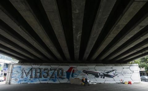 A man walks past graffiti of the missing Malaysia Airlines Flight MH370 in Kuala Lumpur