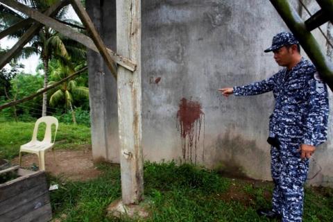 A prison officer points to a wall with blood stains belonging to a prison guard who was killed after gunmen stormed the prison and freed more than 150 inmates, in North Cotabato province, southern Philippines, January 4, 2017. PHOTO BY REUTERS/Marconi Navales