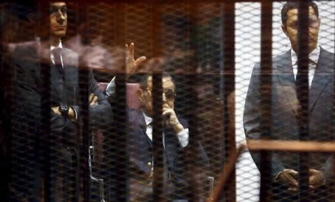 Egypt's former president Hosni Mubarak waves to his supporters with his sons Gamal (L) and Alaa (R) inside a cage in a courtroom during them trial at the police academy, on the outskirts of Cairo, May 9, 2015. PHOTO BY REUTERS/Amr Abdallah