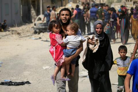 A displaced Iraqi man who fled from clashes, carries children in western Mosul, Iraq, June 3, 2017. PHOTO BY REUTERS/Alaa Al-Marjani