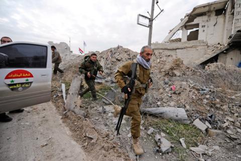 Forces loyal to Syria's President Bashar al-Assad walk past damaged buildings in the government held Sheikh Saeed district of Aleppo, during a media tour, Syria, December 12, 2016. PHOTO BY REUTERS/Omar Sanadiki
