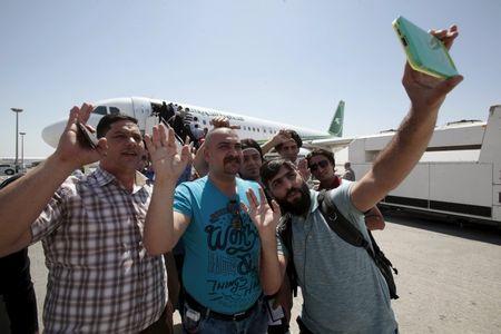 Iraqi men and a member (C) of the Iraqi security forces take selfies as they prepare to leave at the international airport in Najaf, south of Baghdad, September 4, 2015. PHOTO BY REUTERS/Alaa Al-Marjani