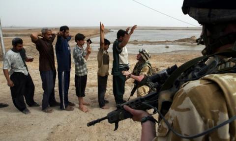 Iraqi men are frisked by a British Army soldier before being allowed to re-enter the southern city of Basra, March 31, 2003. PHOTO BY REUTERS/Chris Helgren