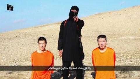 A masked person holding a knife speaks as he stands in between two kneeling men in this still image taken from an online video released by the militant Islamic State group, January 20, 2015. PHOTO BY REUTERS/Social media website via Reuters TV