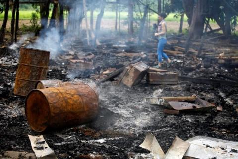 A journalist walks amongst the burnt-out remains of houses at Shwe Lay village, outside of Thandwe in Rakhine state, October 2, 2013. PHOTO BY REUTERS/Soe Zeya Tun