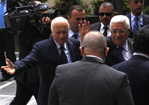 Arab League Chief Nabil al-Arabi (L) greets Palestinian President Mahmoud Abbas, who waves to the media, before attending an Arab Foreign Ministers' meeting at the Arab League headquarters in Cairo