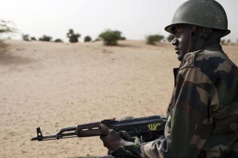 A Malian soldier, holding an AK-47 rifle, rides in a pick-up truck during a military escort outside Timbuktu, Mali