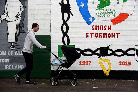 A man pushes a pram past a mural on a wall in the republican Falls Road area of West Belfast in Northern Ireland, September 11, 2015. PHOTO BY REUTERS/Cathal McNaughton
