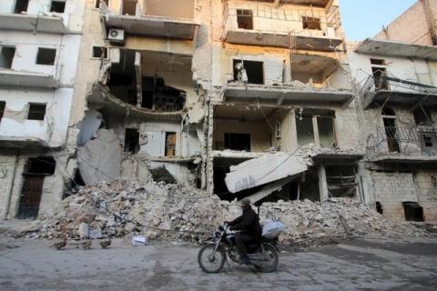 A man rides a motorcycle past damaged buildings in al-Myassar neighborhood of Aleppo, Syria, January 31, 2016. PHOTO BY REUTERS/Abdalrhman Ismail